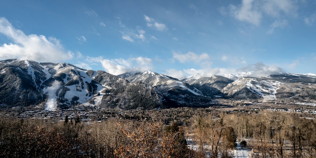 a snow covered mountain range under a cloudy blue sky